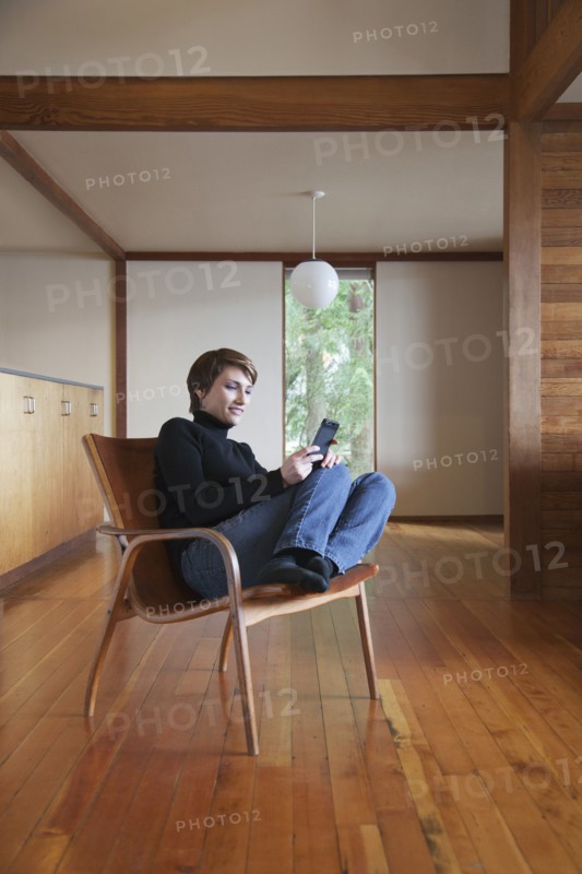 Caucasian woman using cell phone in armchair