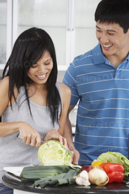 Asian couple chopping vegetables in kitchen