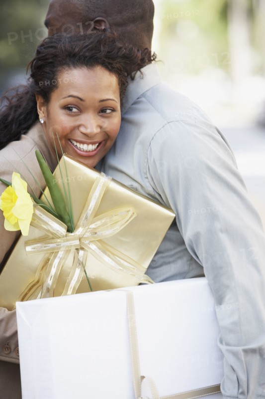 African couple holding gifts and hugging