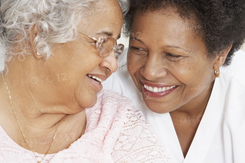 African American mother and adult daughter smiling at each other