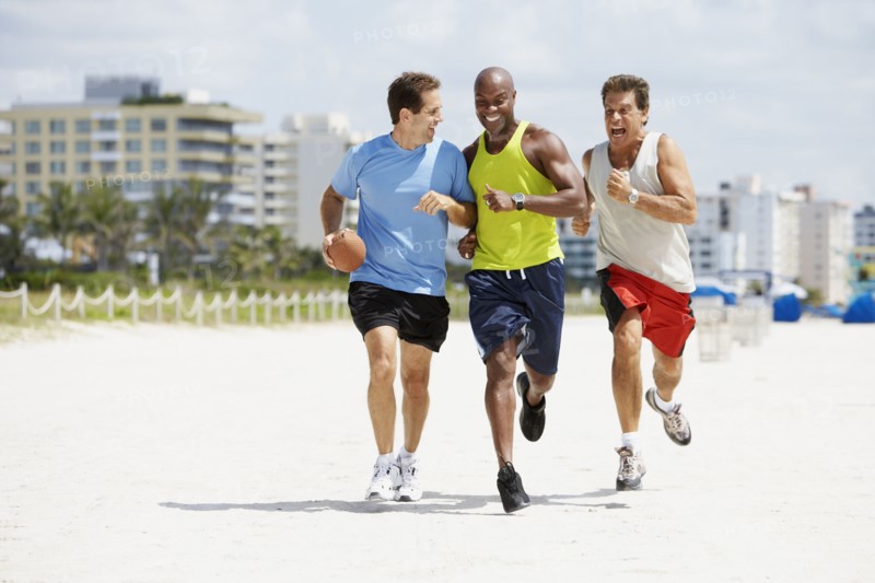 Multi-ethnic men running in beach