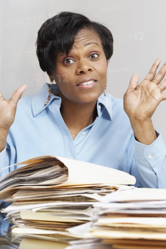 African businesswoman behind stacks of folders