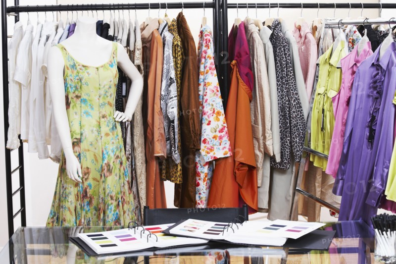 Textile swatches and mannequin in front of clothing rack