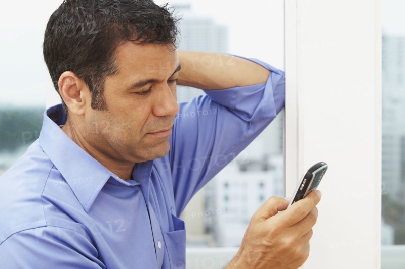 Hispanic businessman text messaging on cell phone