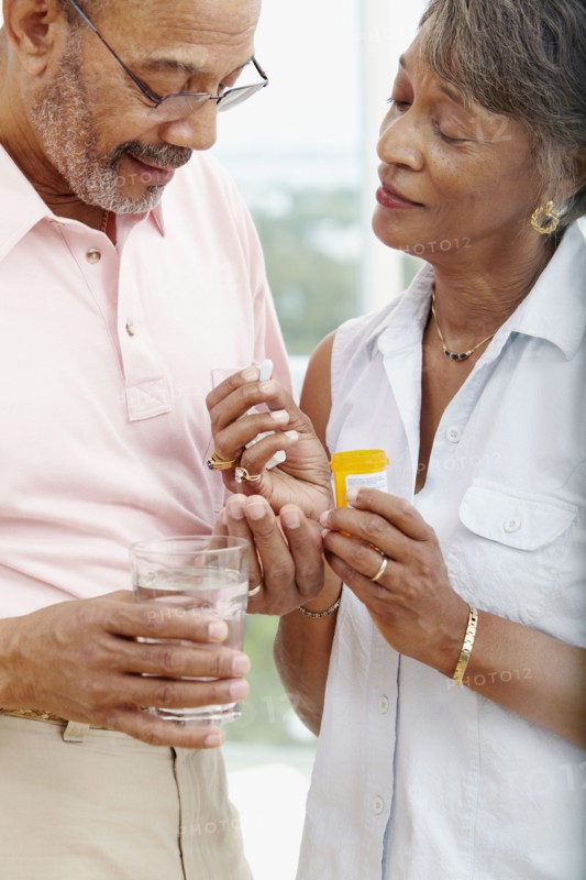 African woman helping husband take medication