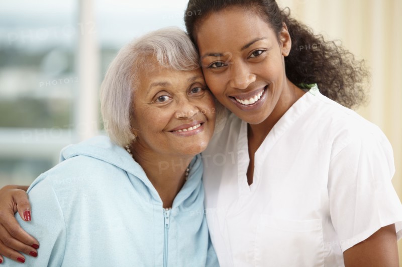 African American nurse hugging senior woman