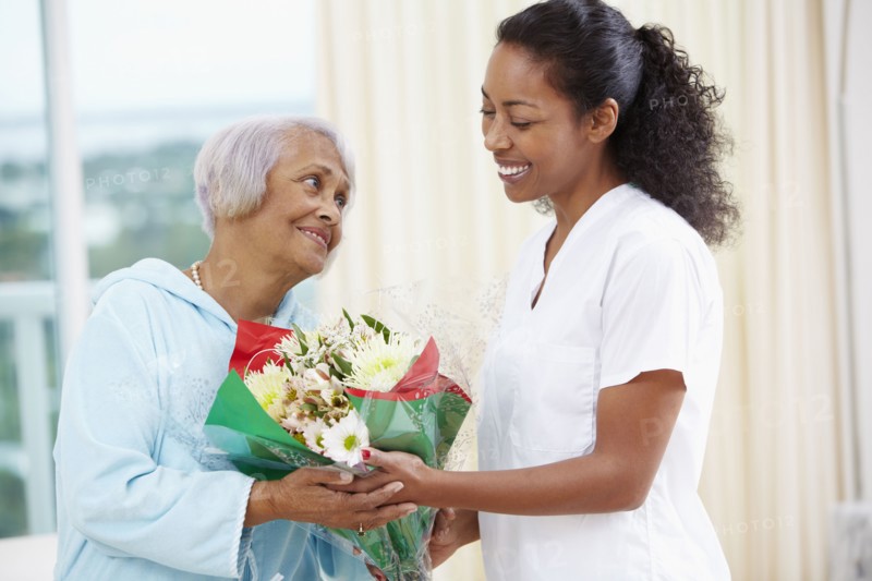 African American woman giving nurse bouquet of flowers