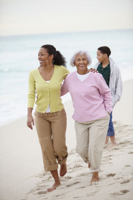 African American woman walking with mother and son on beach