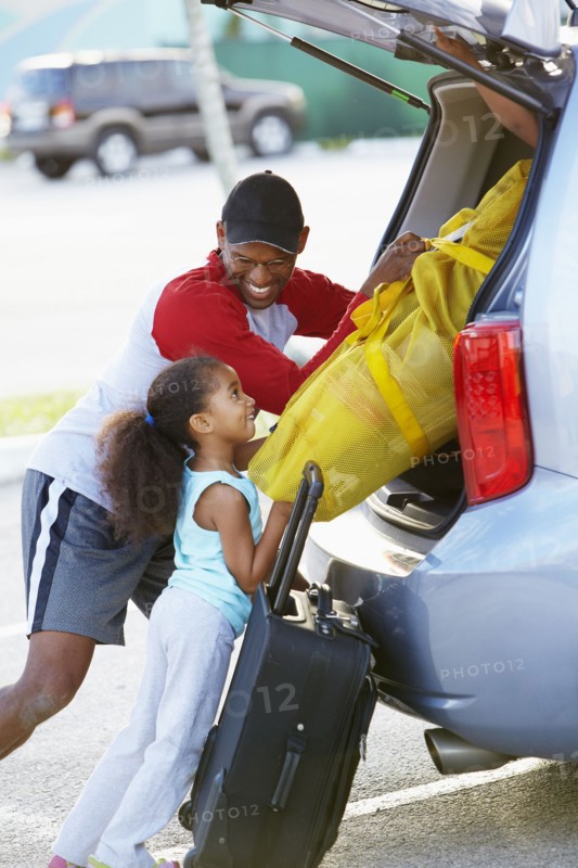 African American father and daughter loading car