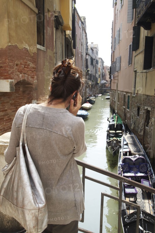 Italian woman talking on cell phone near canal