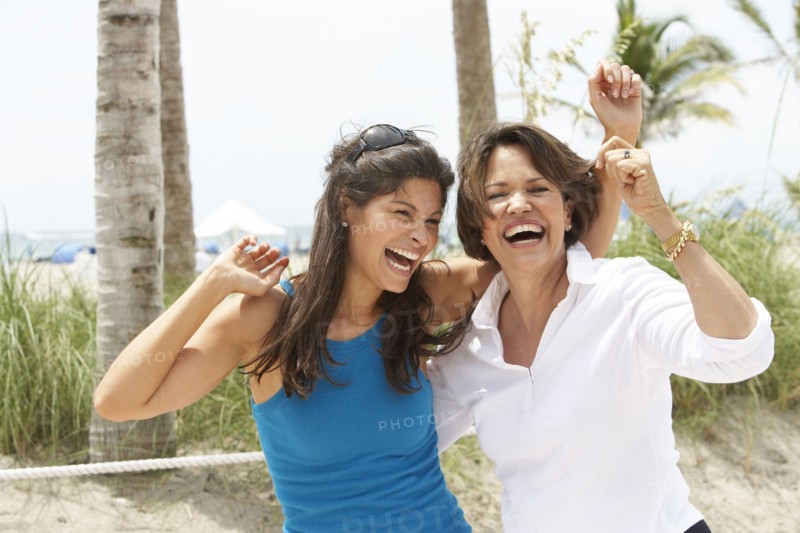 Hispanic mother and daughter laughing on beach