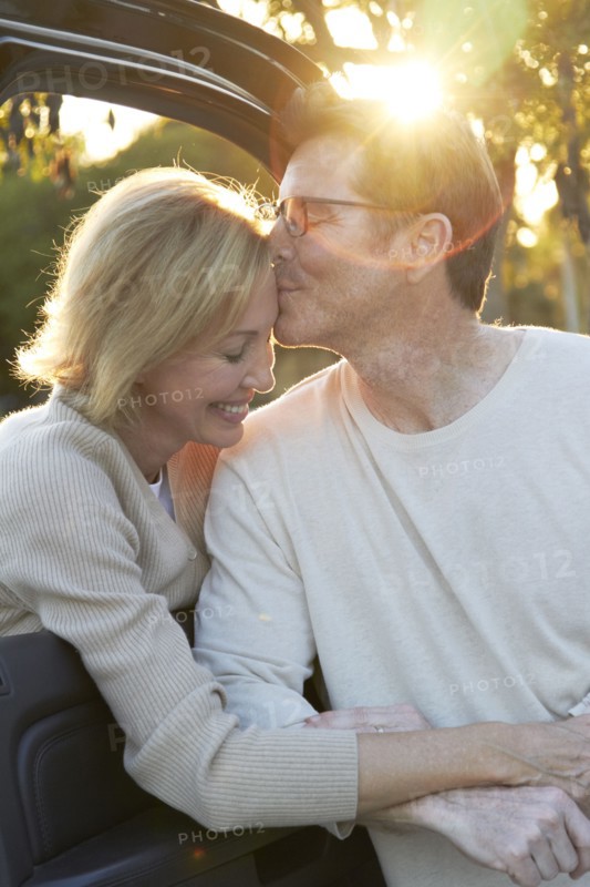 Caucasian couple kissing by car
