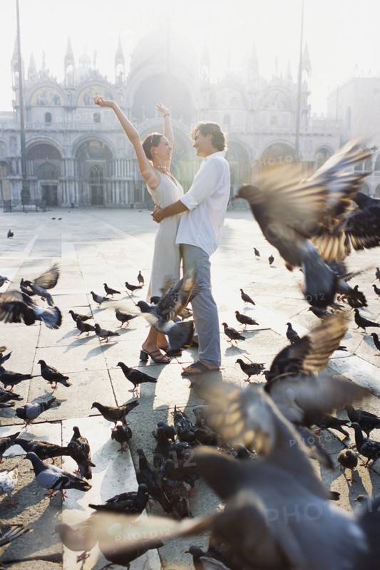 Couple surrounded by pigeons in St. Mark's Square