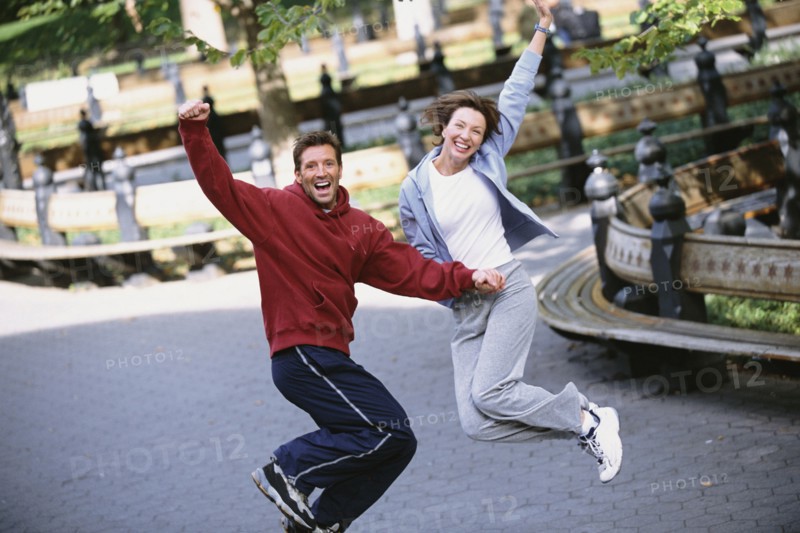 Couple jumping for joy in urban park