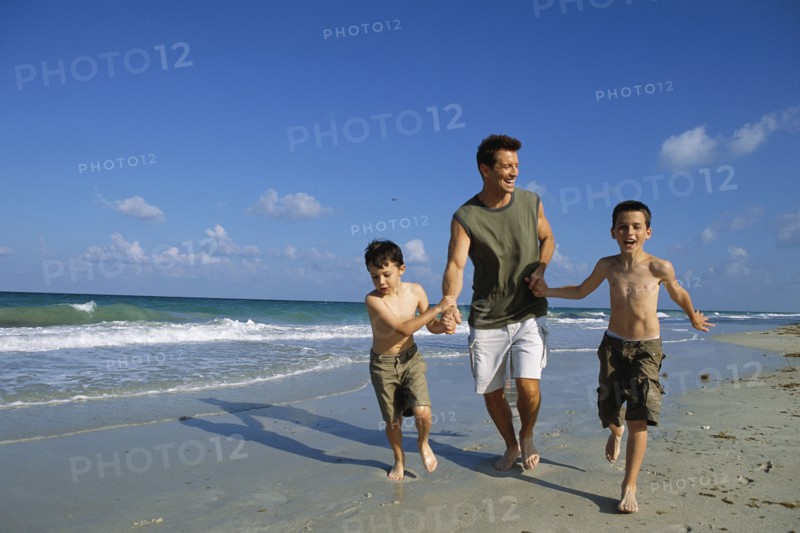 Father and sons walking together on beach