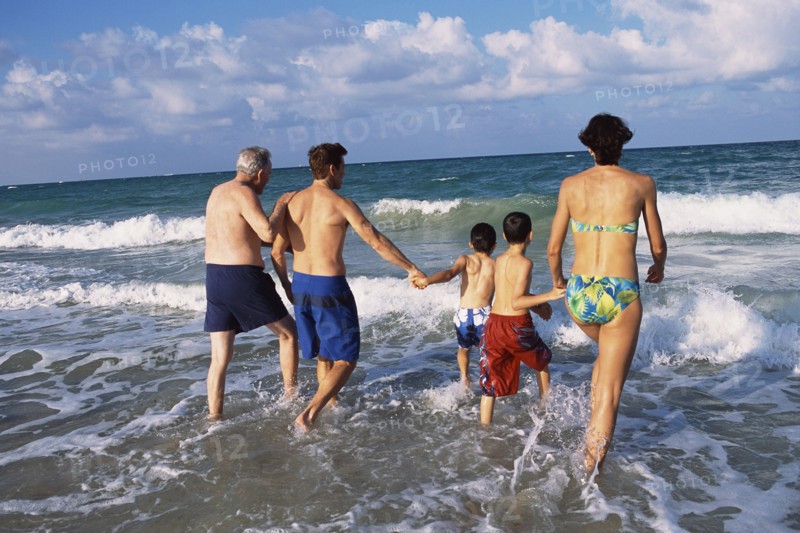 Family walking in waves on beach