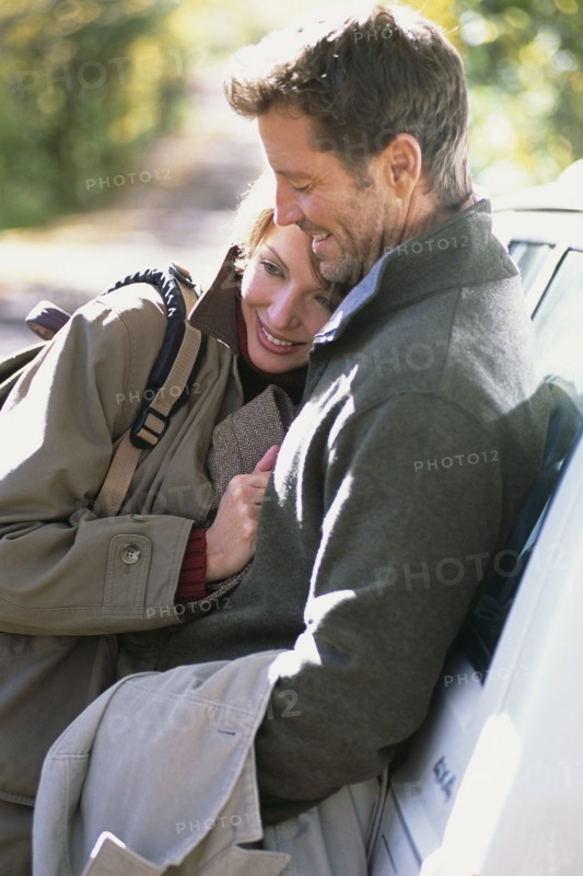 Couple hugging by car
