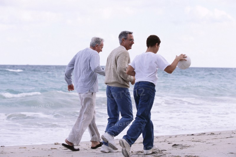 Three generations of Caucasian men walking on beach