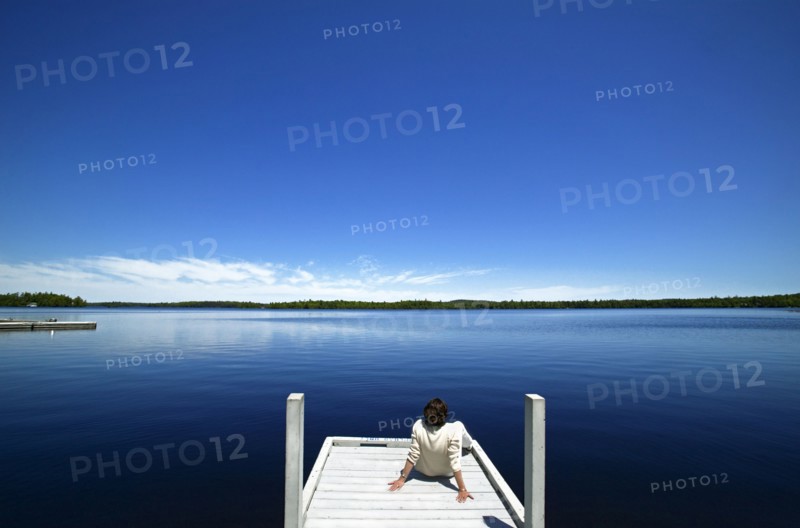 Woman overlooking lake on wooden dock