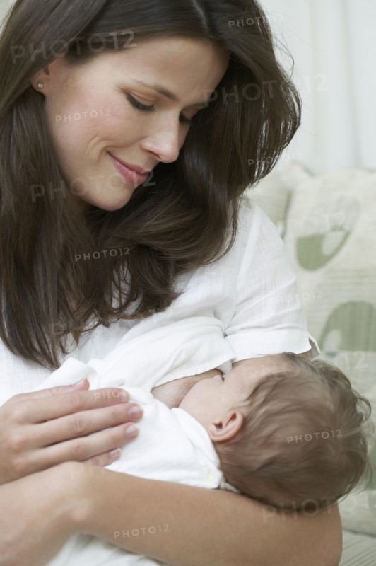Mother breastfeeding baby on sofa