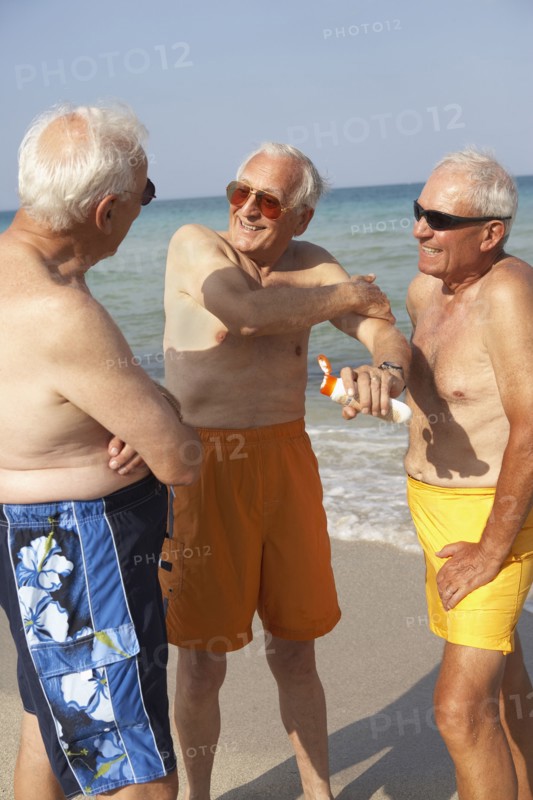 Senior men applying sunscreen on beach