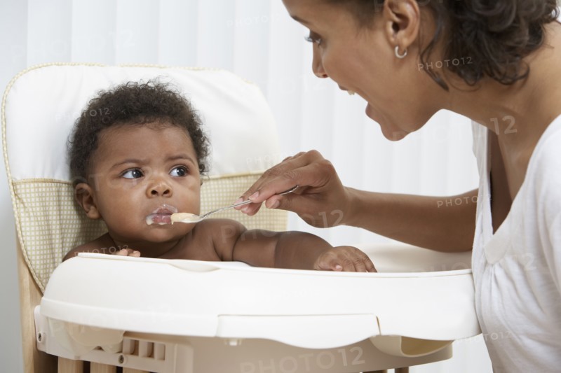 Mother feeding baby in high chair