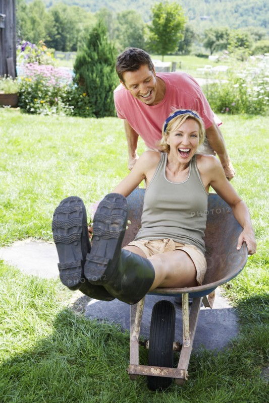 Man pushing girlfriend in wheelbarrow