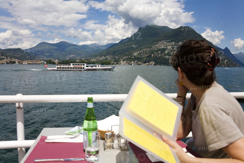 Woman reading menu in restaurant overlooking rural lake