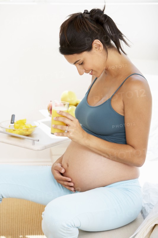 Pregnant Hispanic woman drinking fruit juice