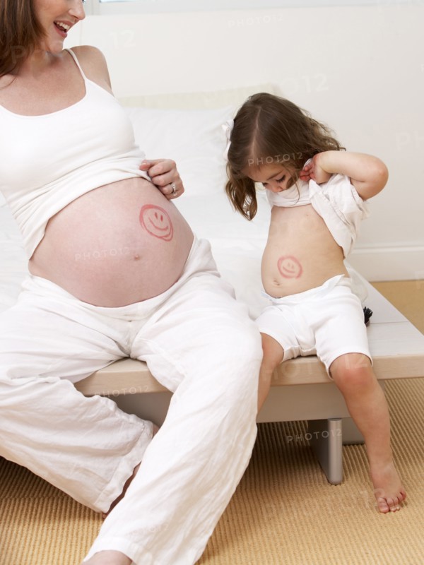 Caucasian girl and pregnant mother with drawings on bellies