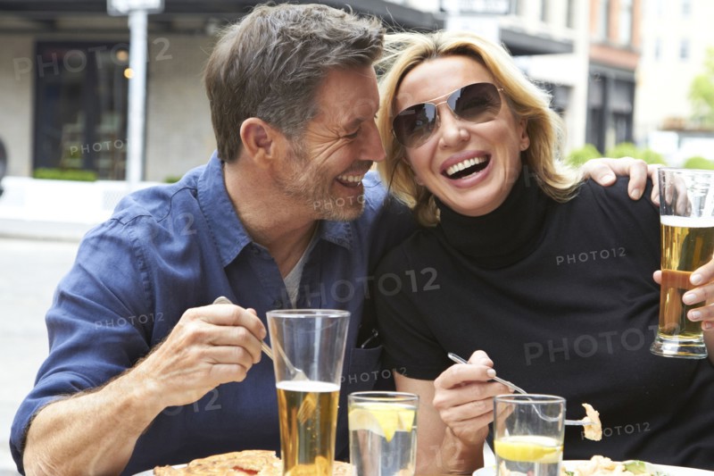 Caucasian couple drinking and eating at sidewalk cafe