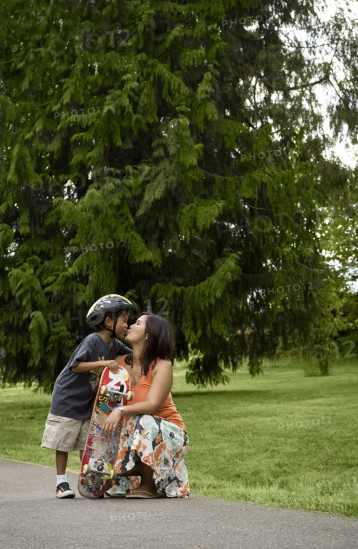 Asian boy with skateboard kissing mother
