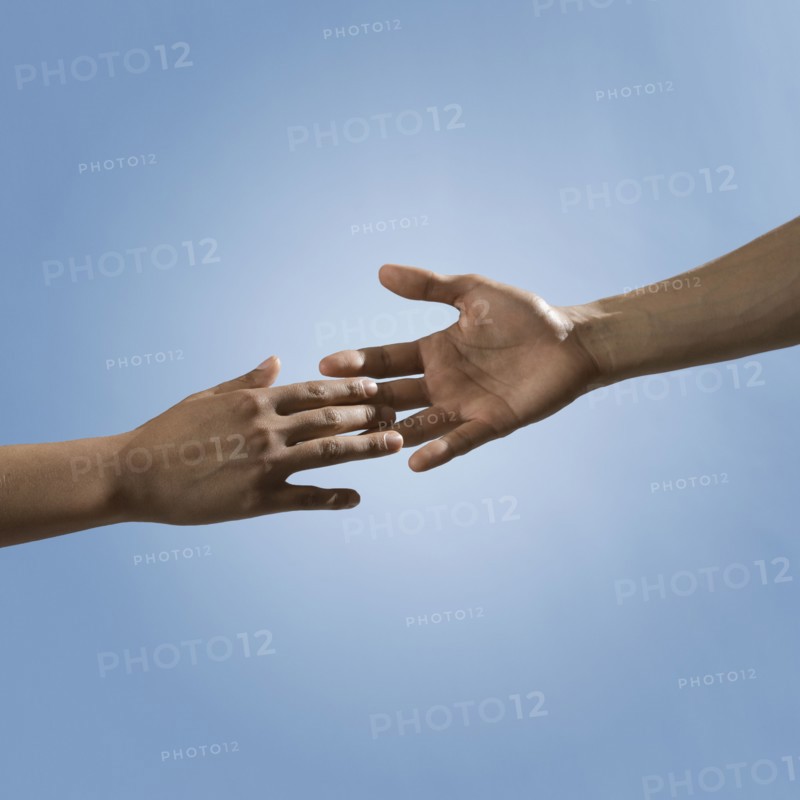 Mixed race people reaching out hands toward one another