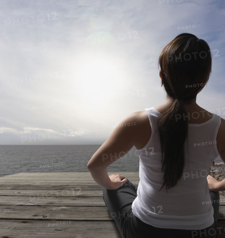 Filipino woman sitting on dock near ocean