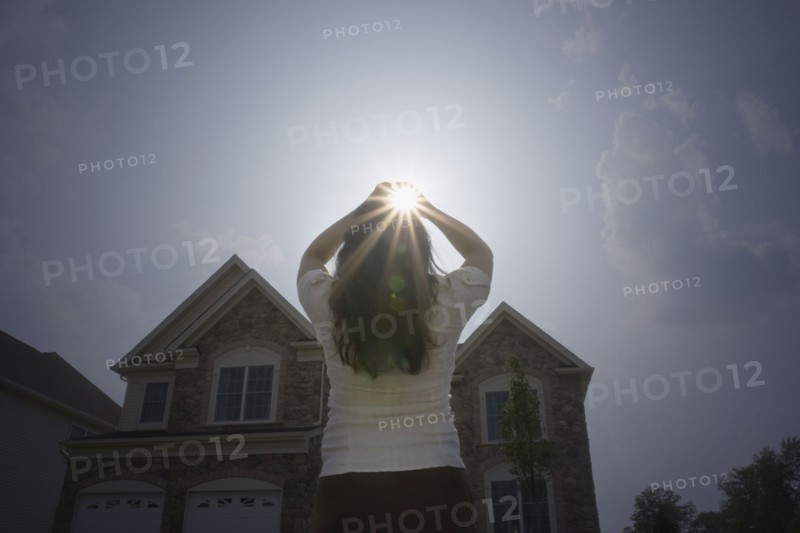 Chinese woman with arms raised looking at sun