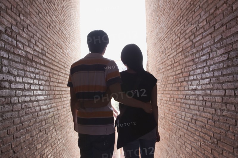 Asian couple walking between brick walls
