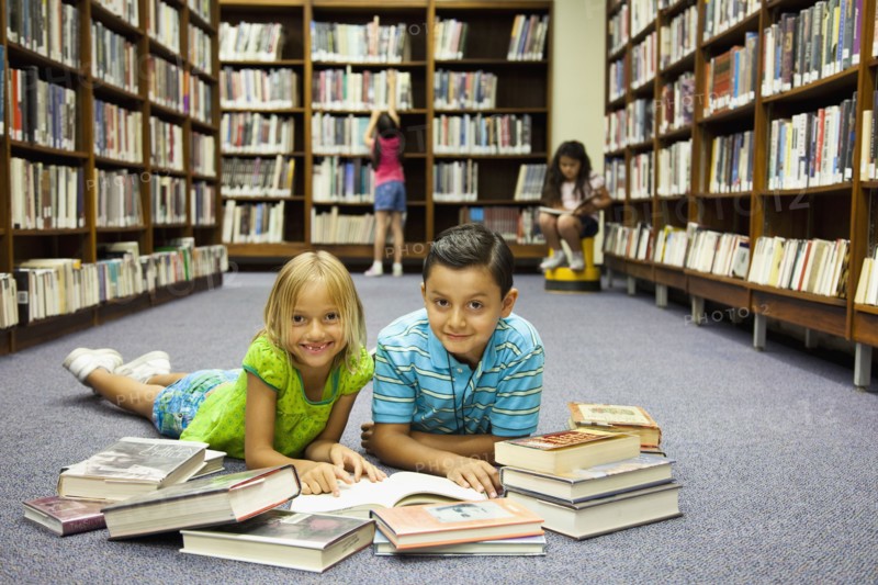 Children reading books on library floor
