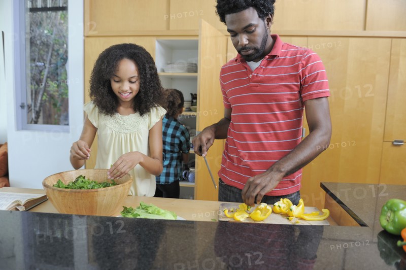 Father and daughters preparing food in kitchen