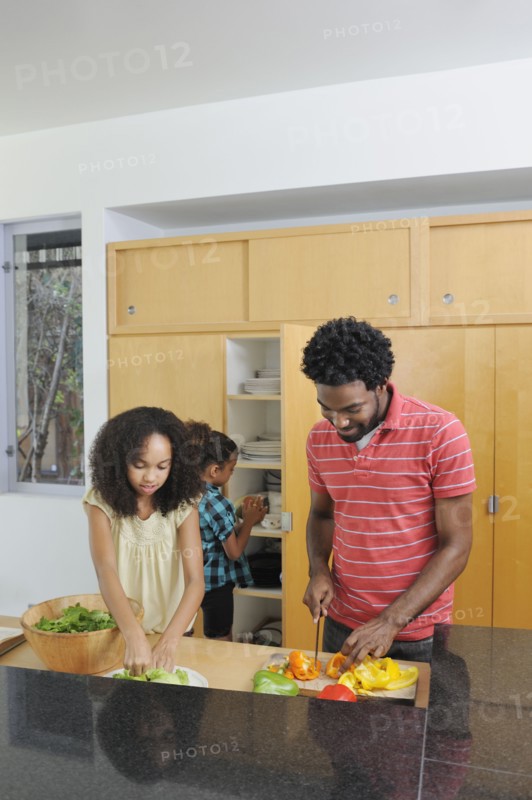 Father and daughters preparing food in kitchen