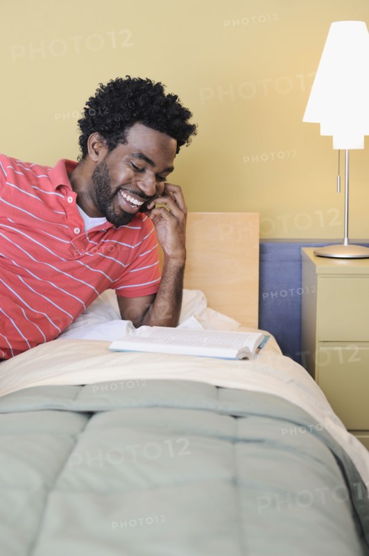 Black man in bedroom talking on cell phone