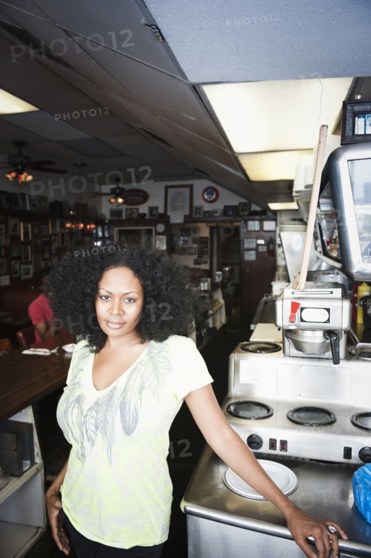 Smiling mixed race woman standing behind counter in diner