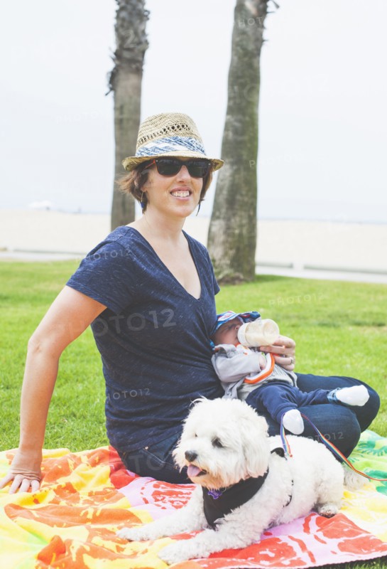 Mother and newborn baby sitting with dog in park