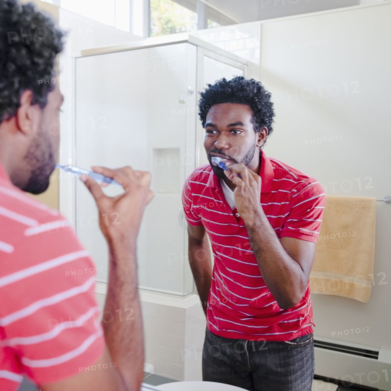 Black man in bathroom brushing teeth