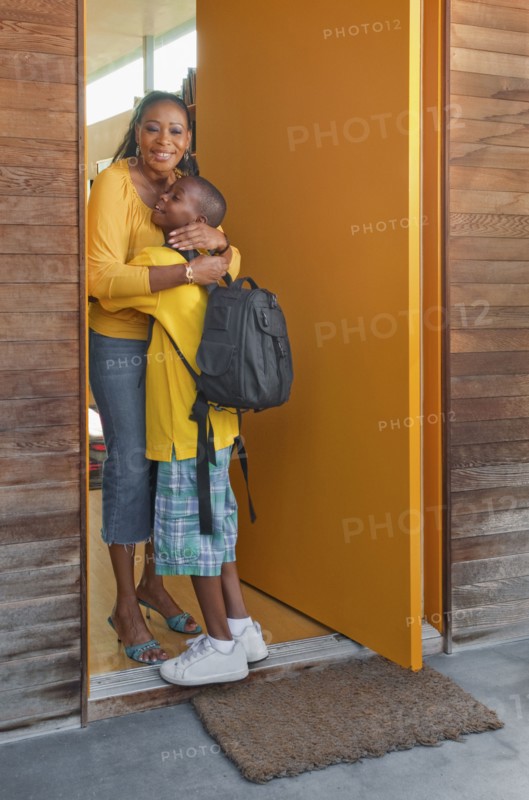 Black mother greeting son at front door