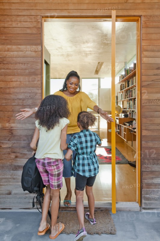 Black mother greeting daughters at front door