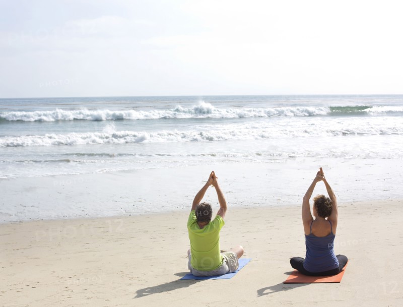 Caucasian couple meditating on beach