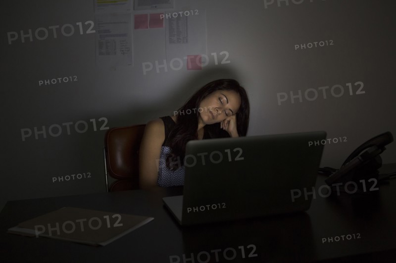 Businesswoman sleeping at desk at night