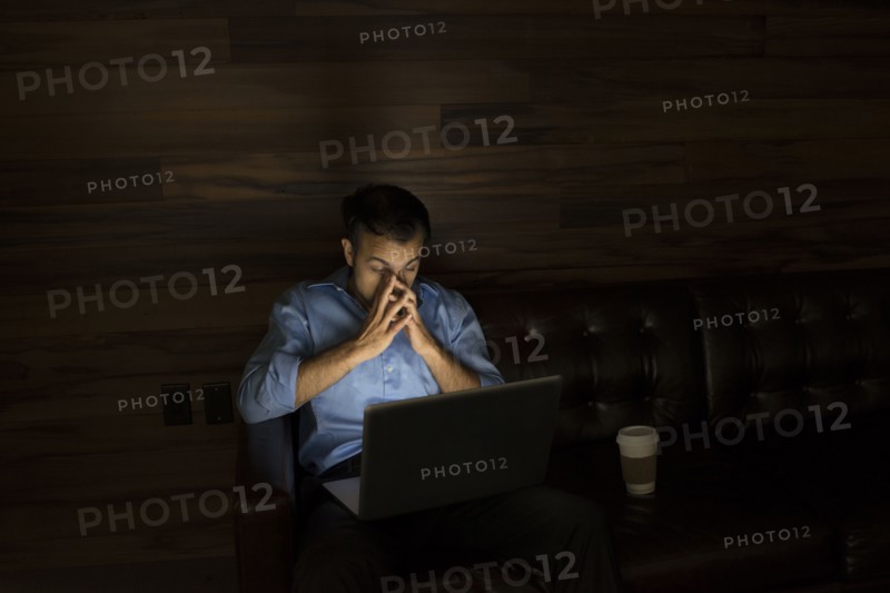 Businessman using laptop on sofa at night