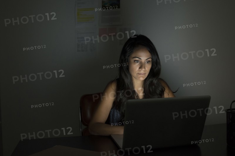 Businesswoman working at laptop at night