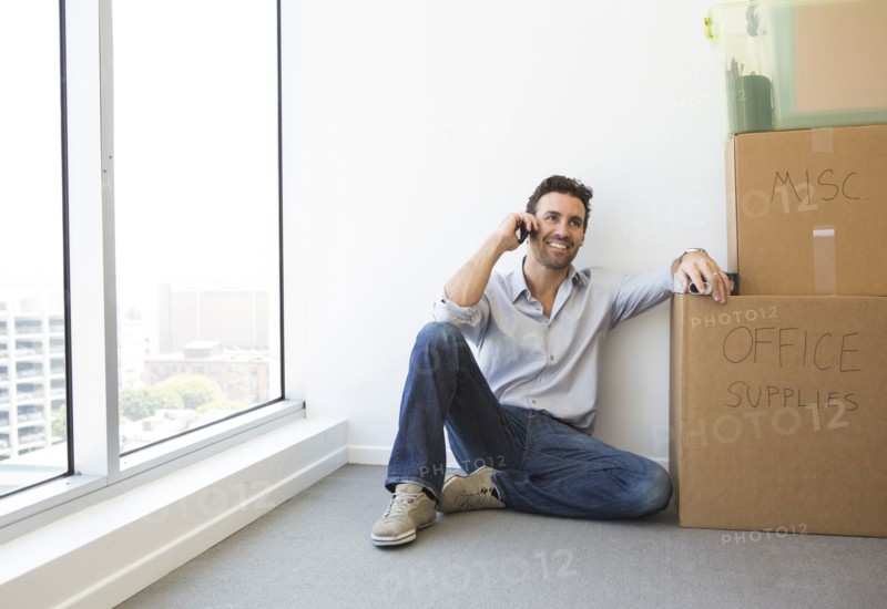 Hispanic businessman on cell phone in new office